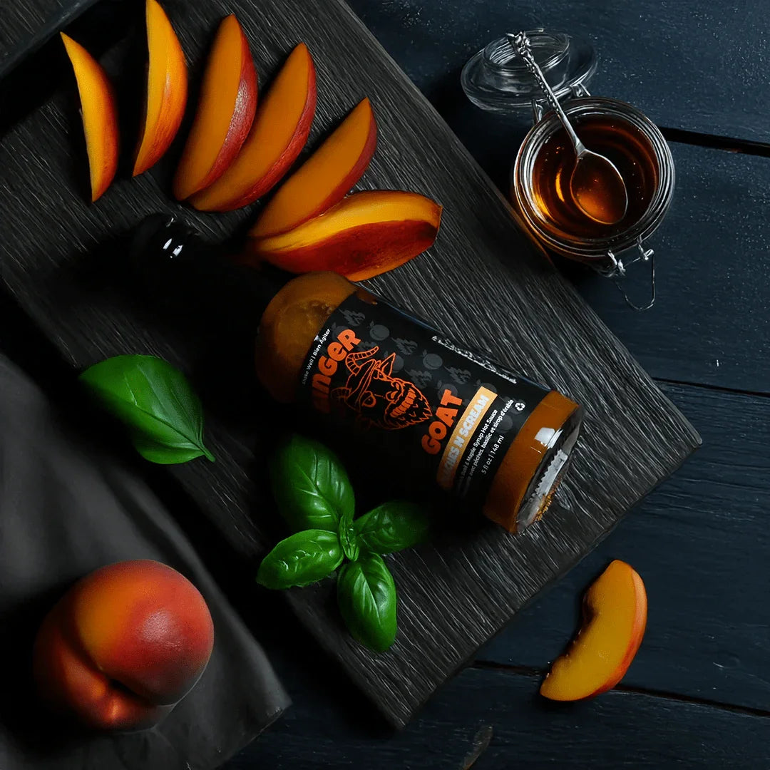 Peaches N Scream hot sauce bottle with peach slices, basil, and honey on dark wood background