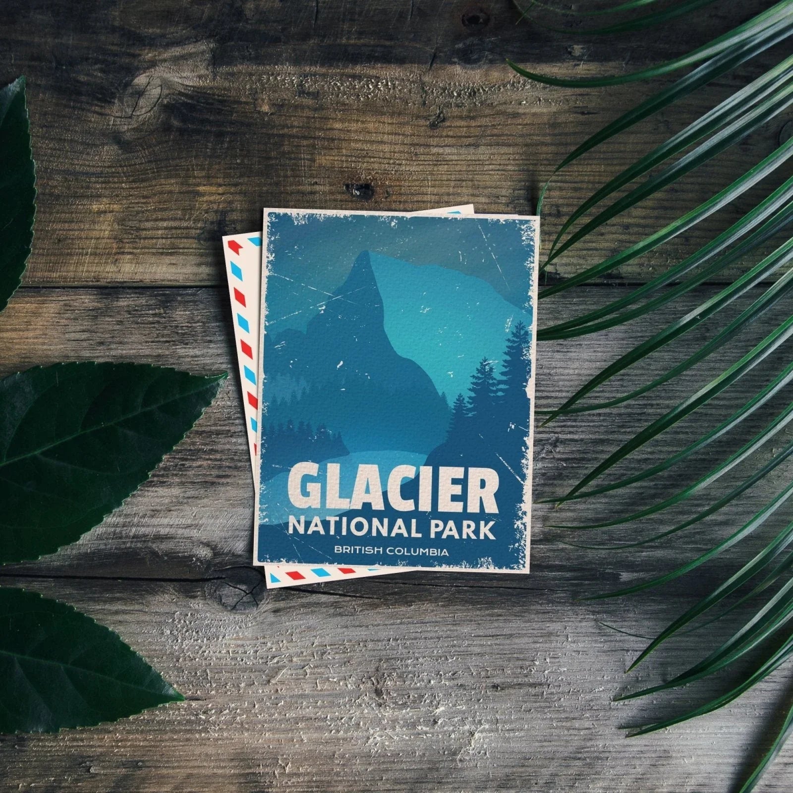 Glacier National Park British Columbia postcard on rustic wood with green leaves