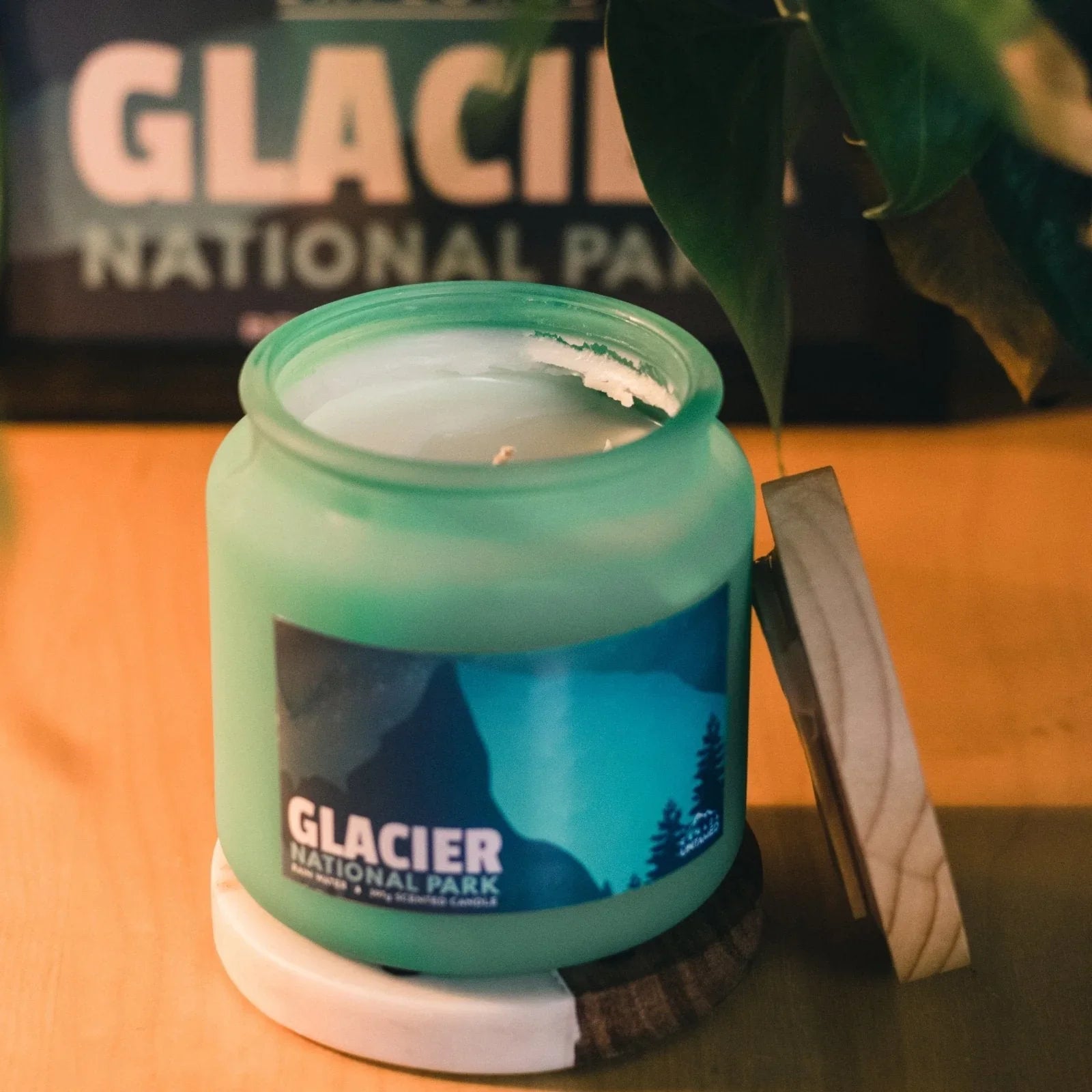 Glacier National Park rain water scented candle in green glass jar on wood table