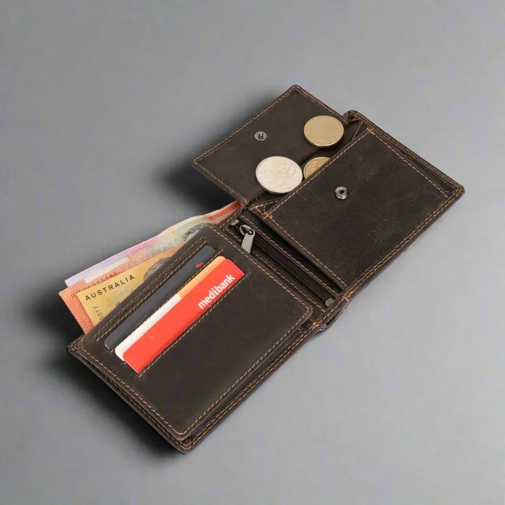 Open brown leather wallet with cards, coins, and Australian banknotes on grey background