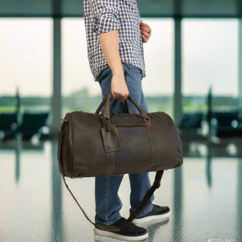 Man holding brown leather duffel bag in airport terminal, travel luggage concept