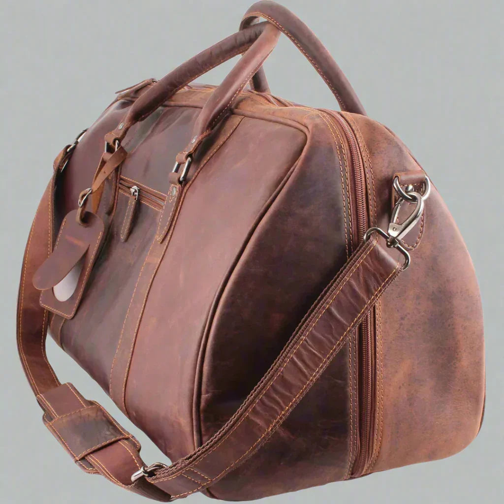 Brown leather travel bag with shoulder strap and tags against a plain background
