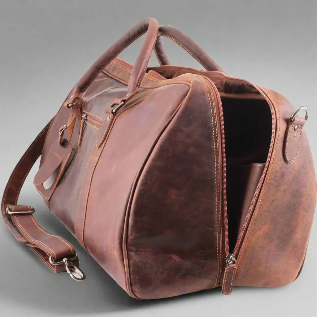 Brown leather travel bag with shoulder strap and zippered opening on a plain background