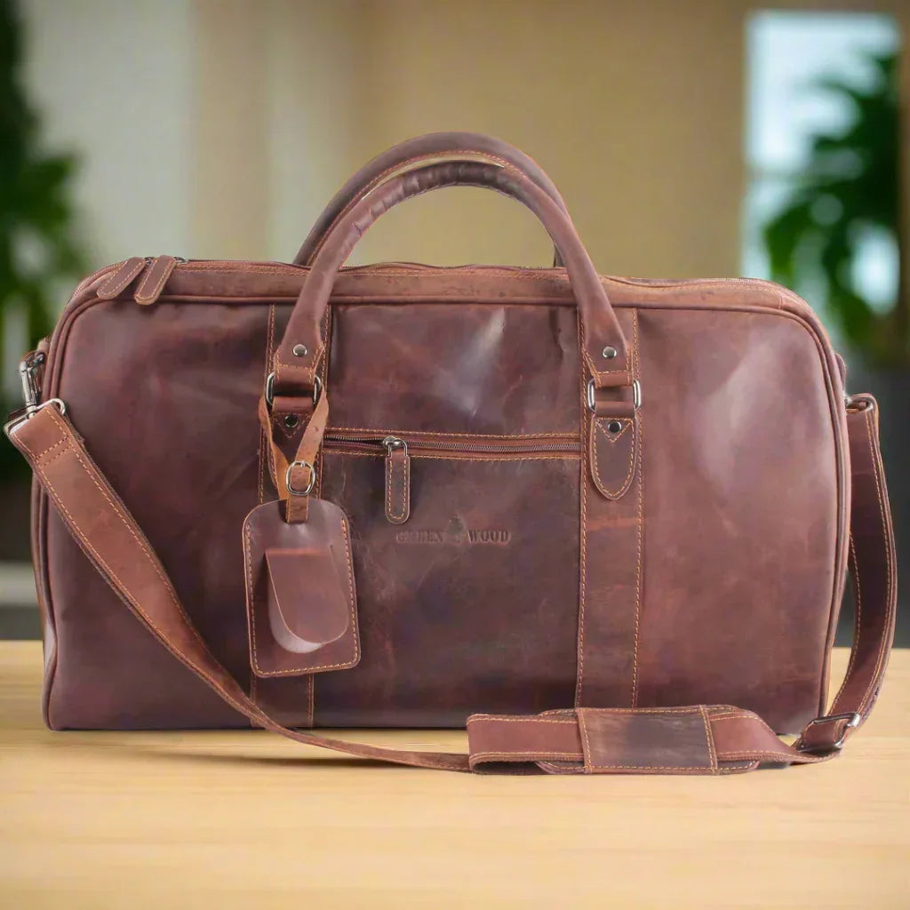 Brown leather duffel bag with shoulder strap on wooden table, travel bag style