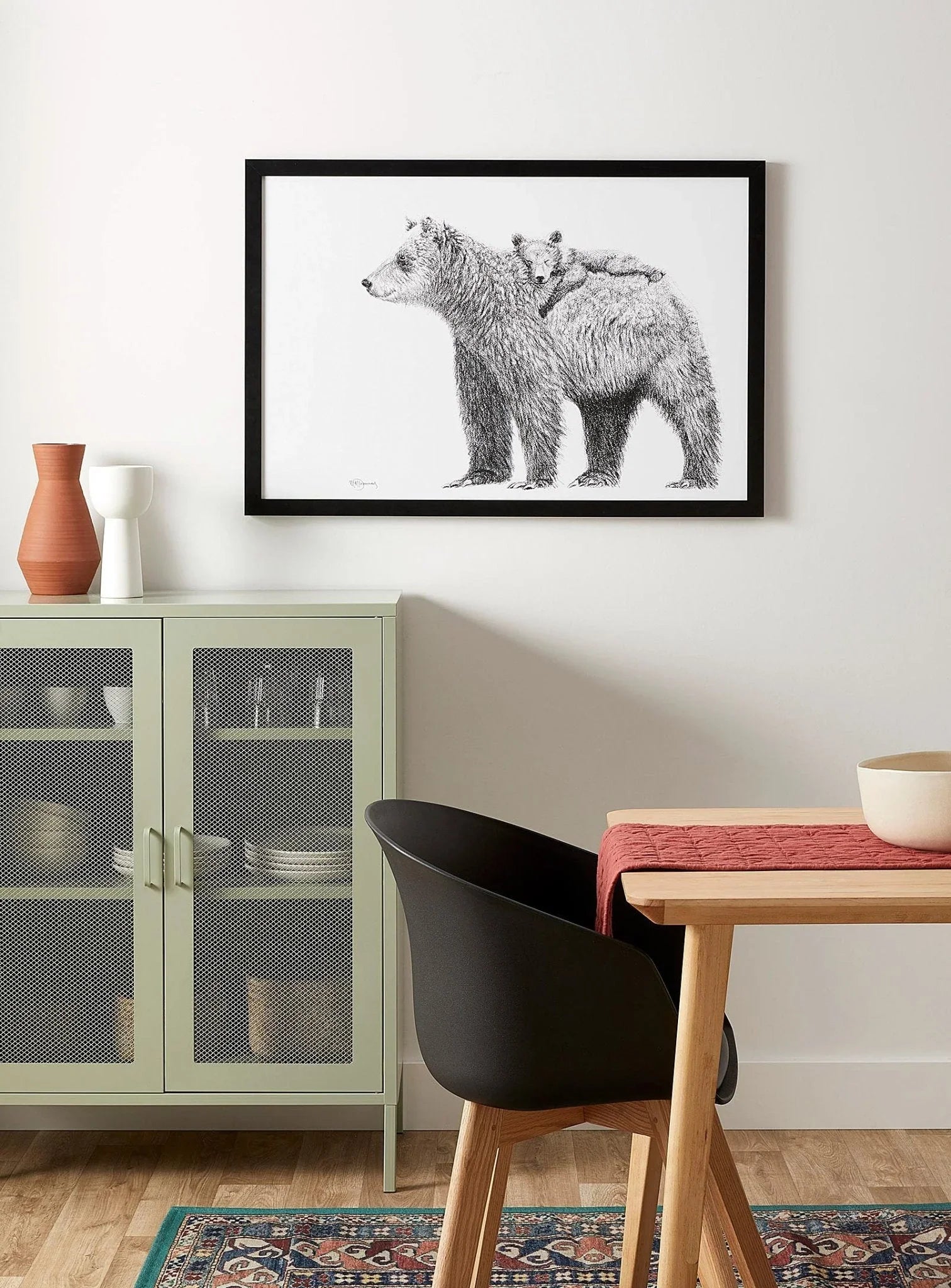 Framed black and white bear and cub wall art in modern dining room with green cabinet