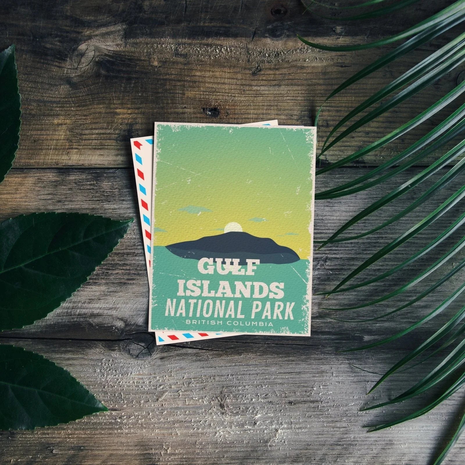 Gulf Islands National Park postcard on wooden table with green leaves, British Columbia