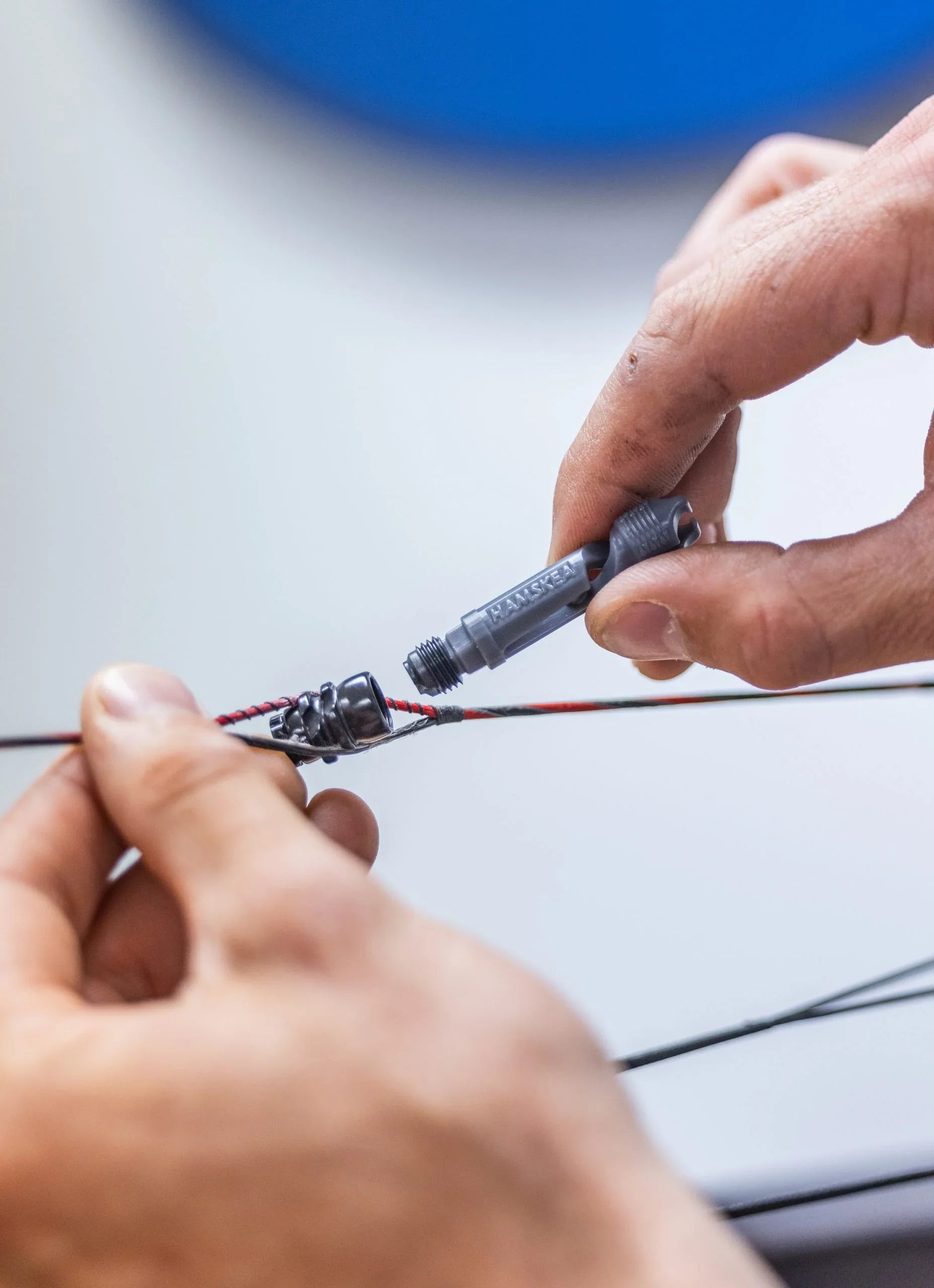 Hands installing Hamskea archery string dampener on a bow string up close