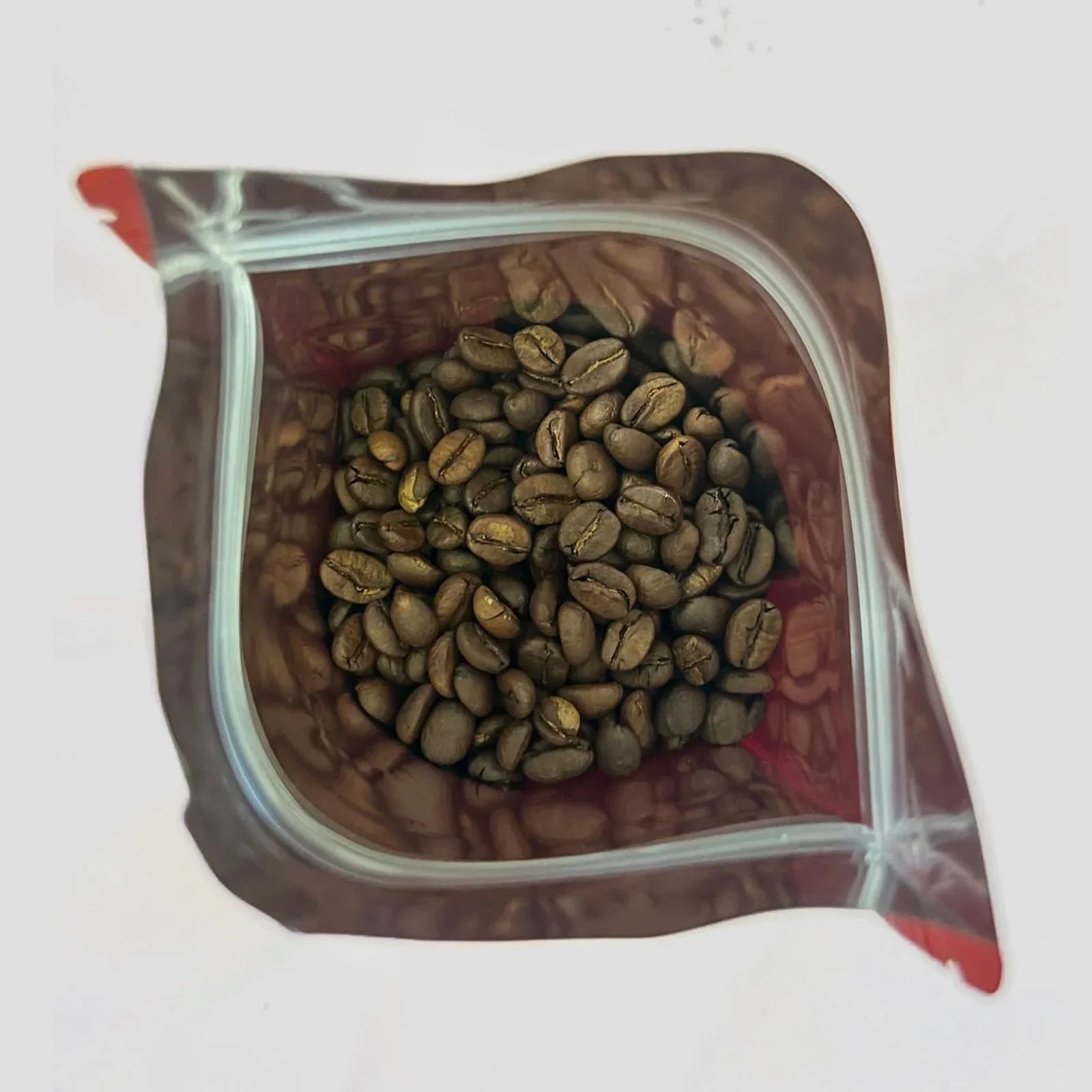 Top view of coffee beans inside an open brown resealable bag on a white background