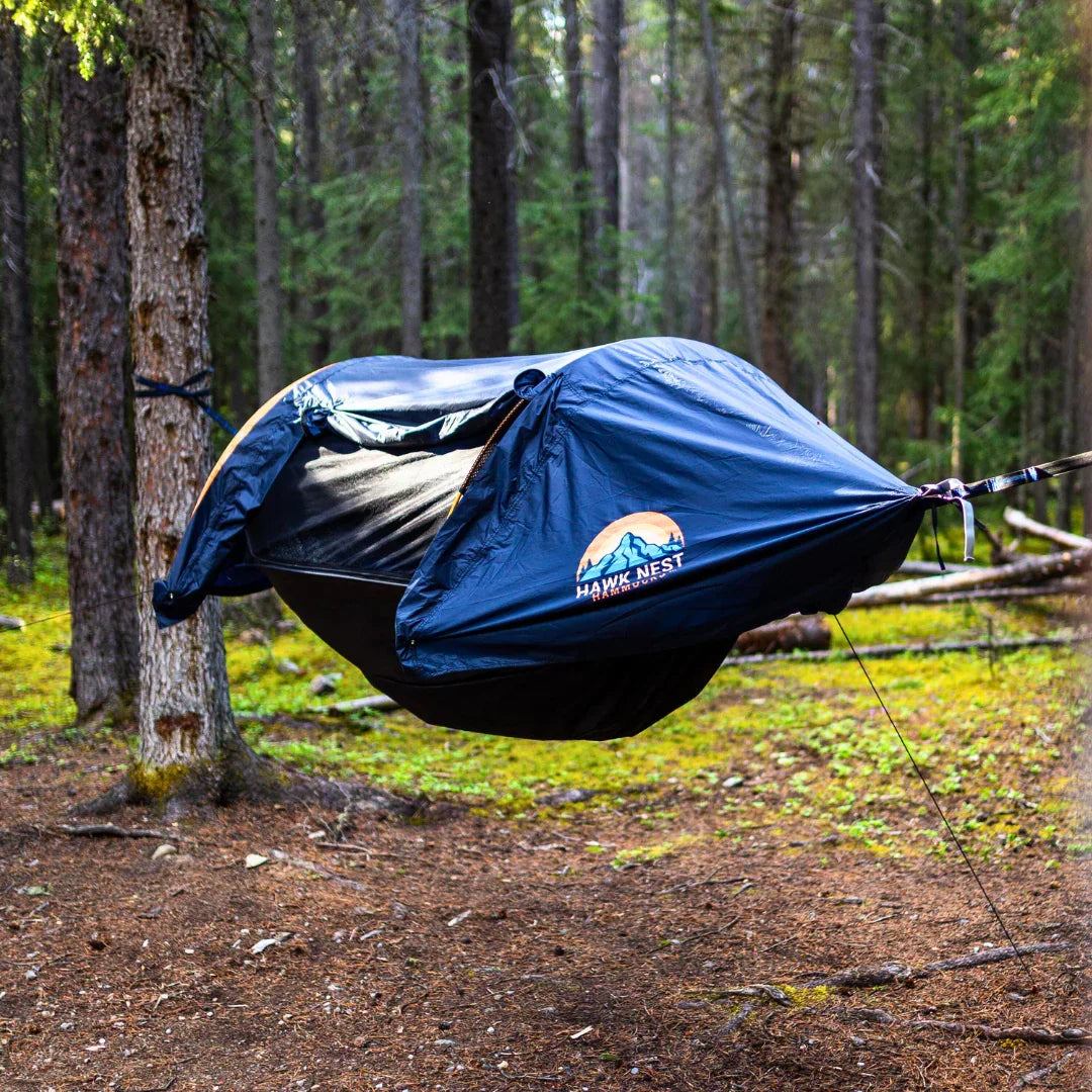 Hawk Nest camping hammock tent suspended between trees in a forest setting