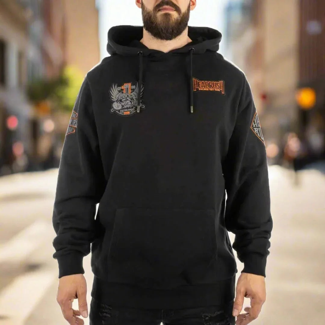 Man wearing black Headrush Worldwide pullover hoodie with graphic logos, standing on city street