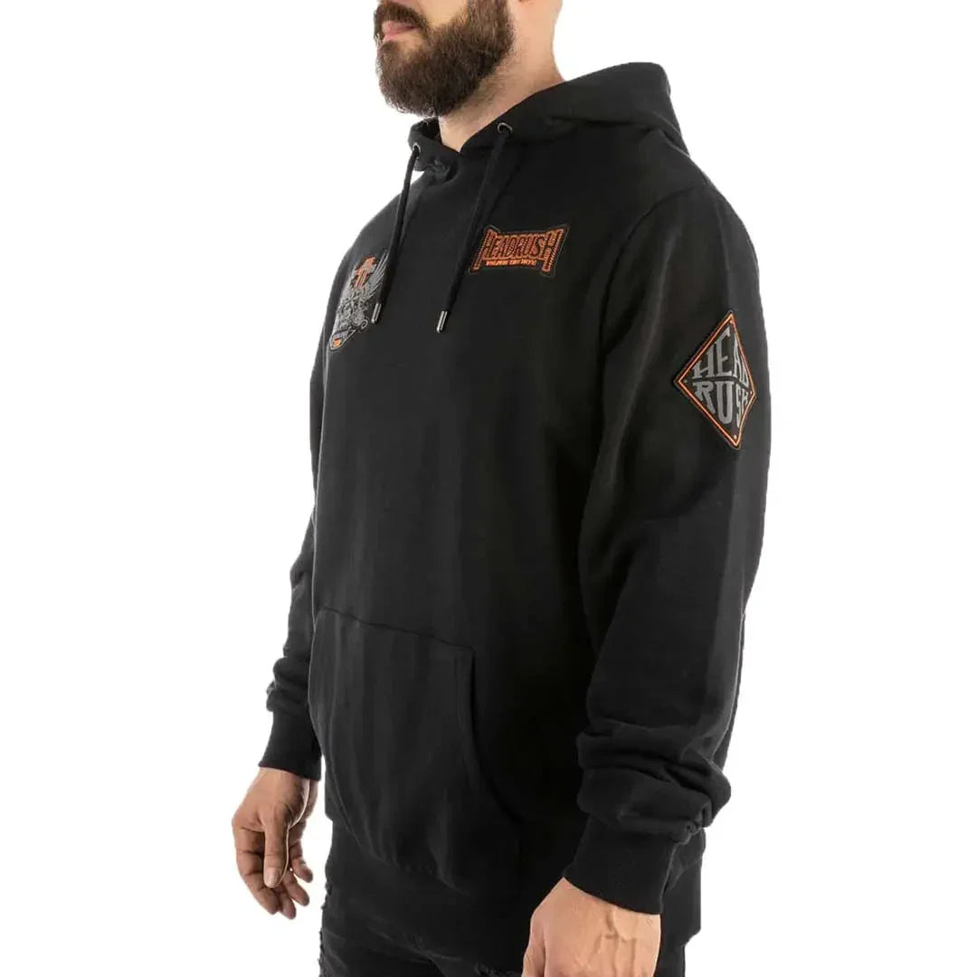 Man wearing Headrush Worldwide black pullover hoodie with graphic patches and front pocket