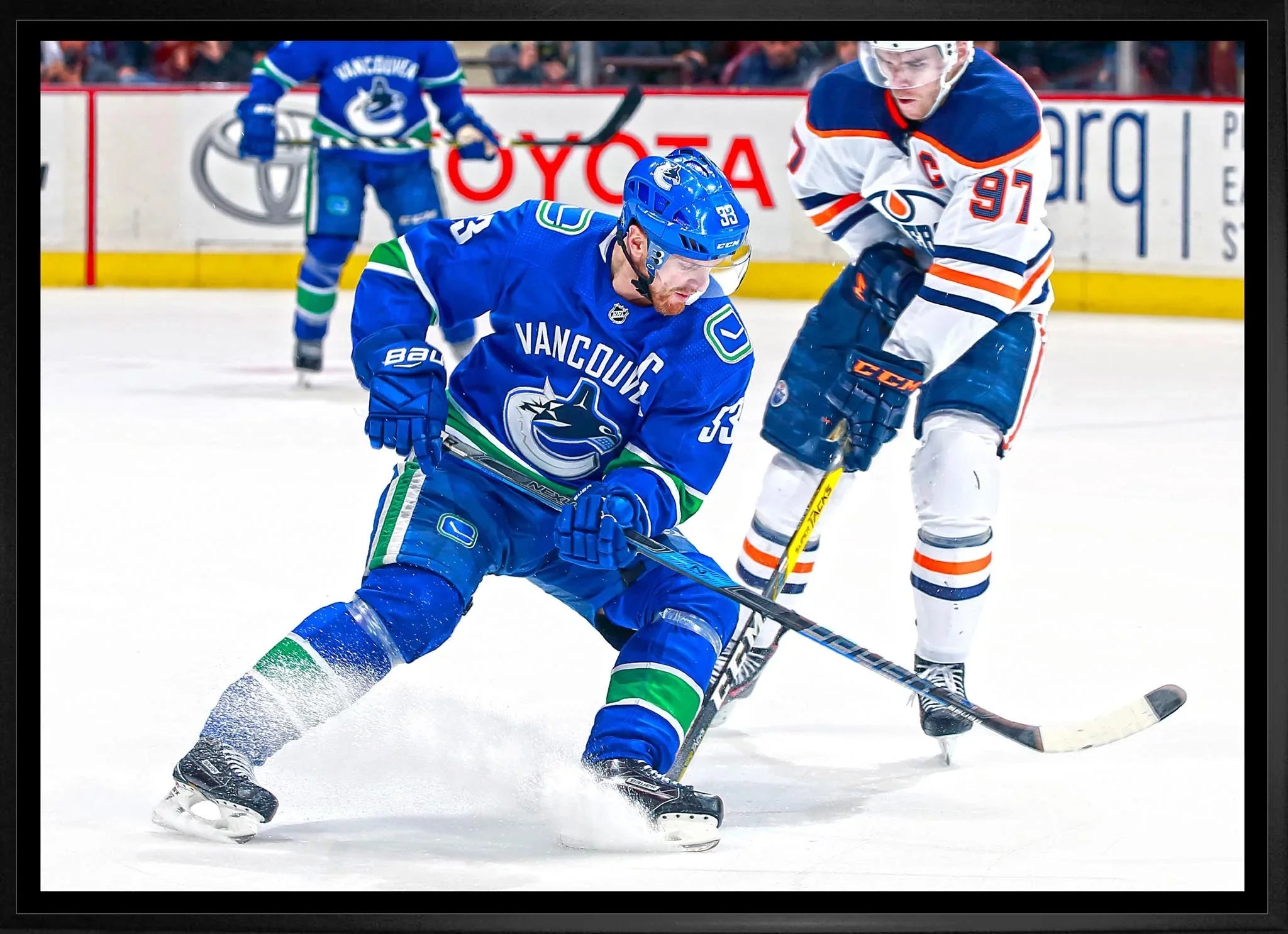 Vancouver Canucks player in blue jersey skating with puck against Edmonton Oilers in NHL game
