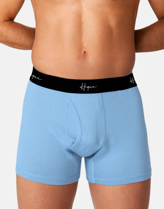 Man wearing light blue boxer briefs with black Hiqua waistband on white background