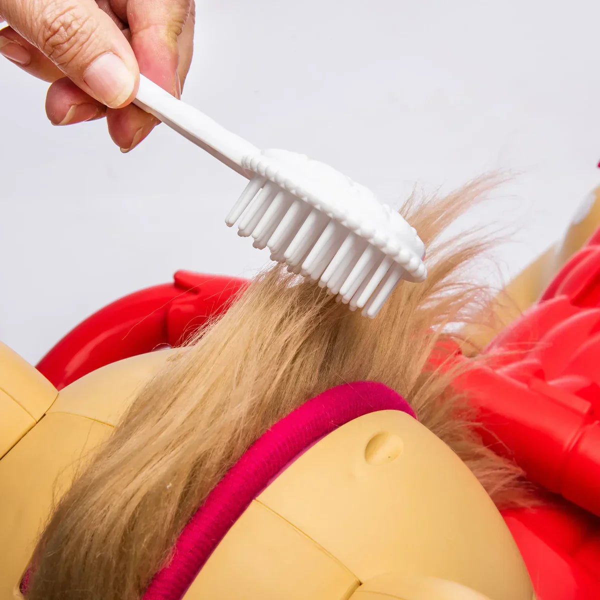 Hand brushing toy horse mane with white brush, close-up, kids grooming toy