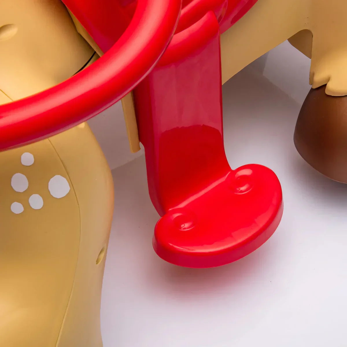 Close-up of red plastic footrest and tan spotted body on children's horse rocker toy