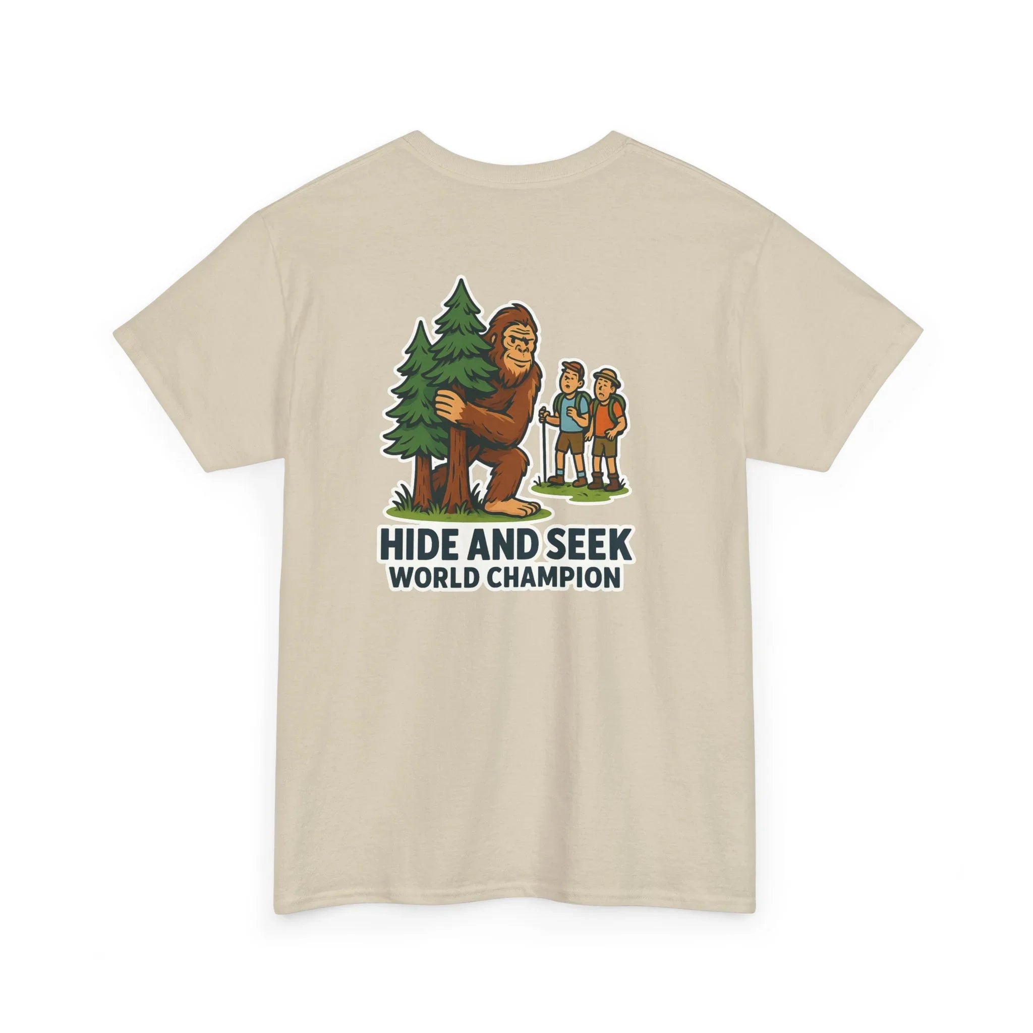 Beige t-shirt with cartoon Bigfoot hiding behind a tree, hikers, and 'Hide and Seek World Champion' text.