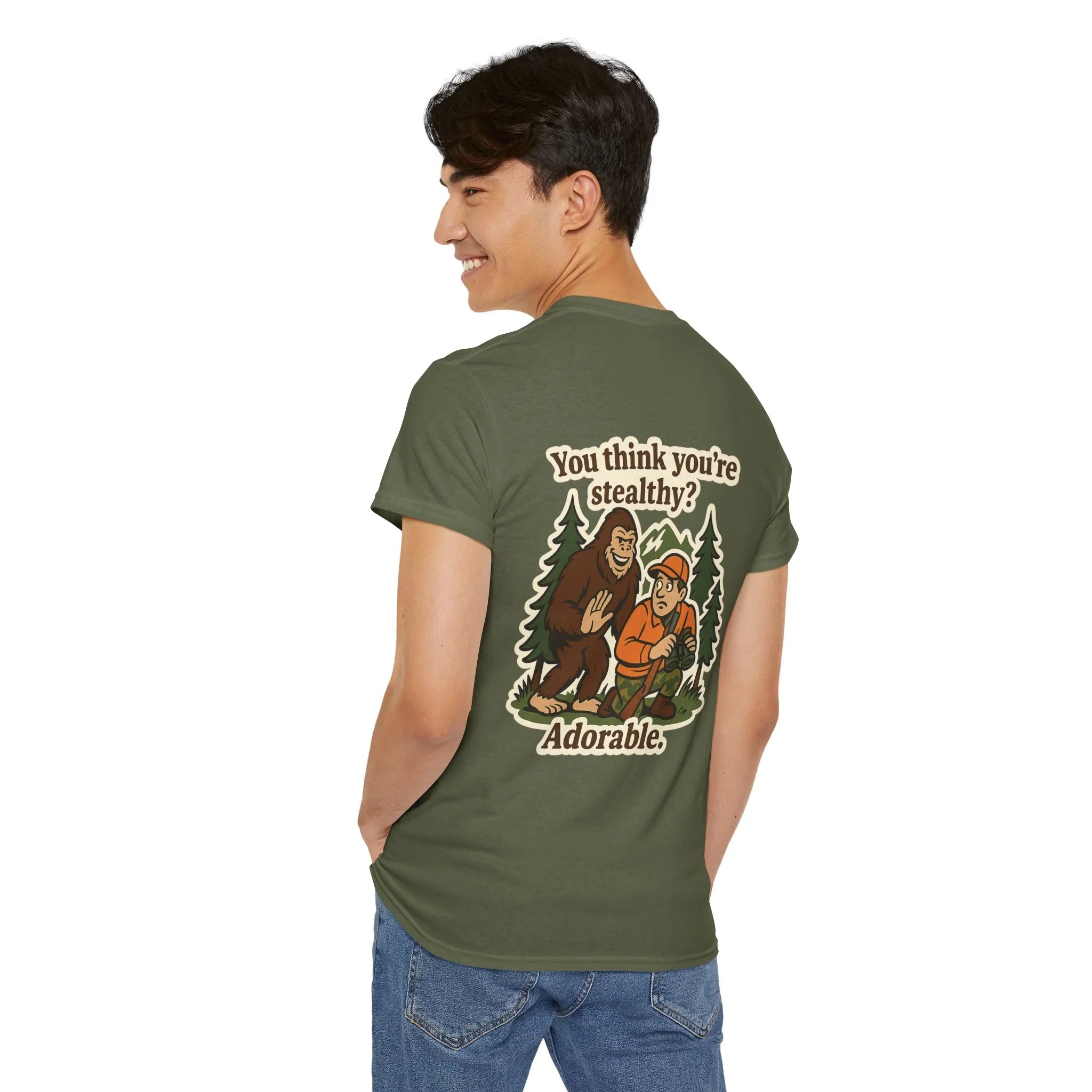 Man wearing green graphic T-shirt with Bigfoot and hiker illustration, outdoorsy humor design