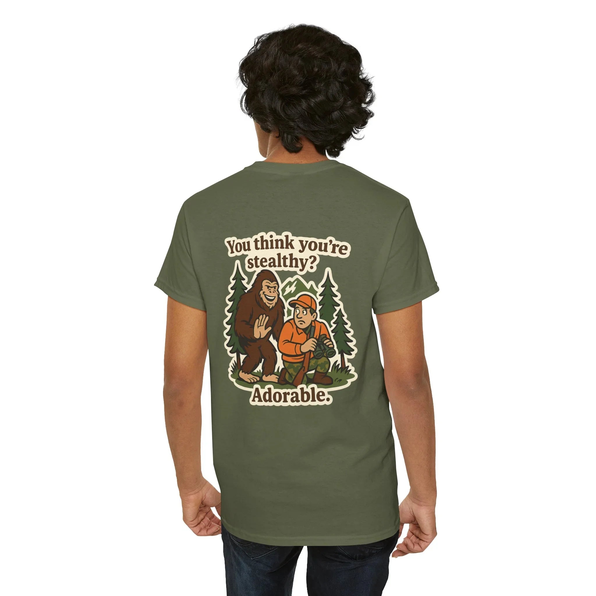 Man wearing green t-shirt with Bigfoot cartoon, trees, and 'You think you’re stealthy? Adorable.'