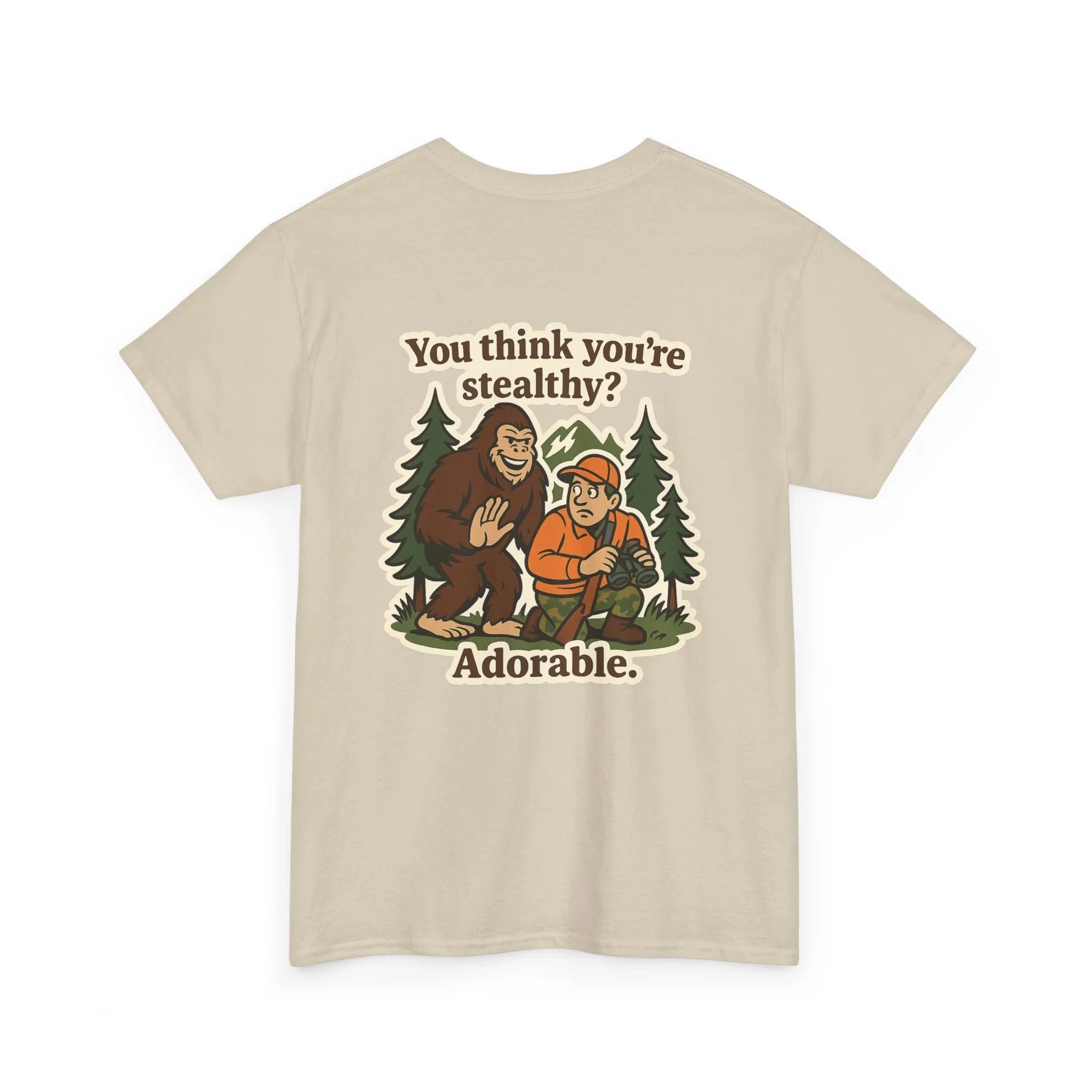 Beige t-shirt with cartoon Bigfoot, hunter, trees, and 'You think you’re stealthy? Adorable.' text