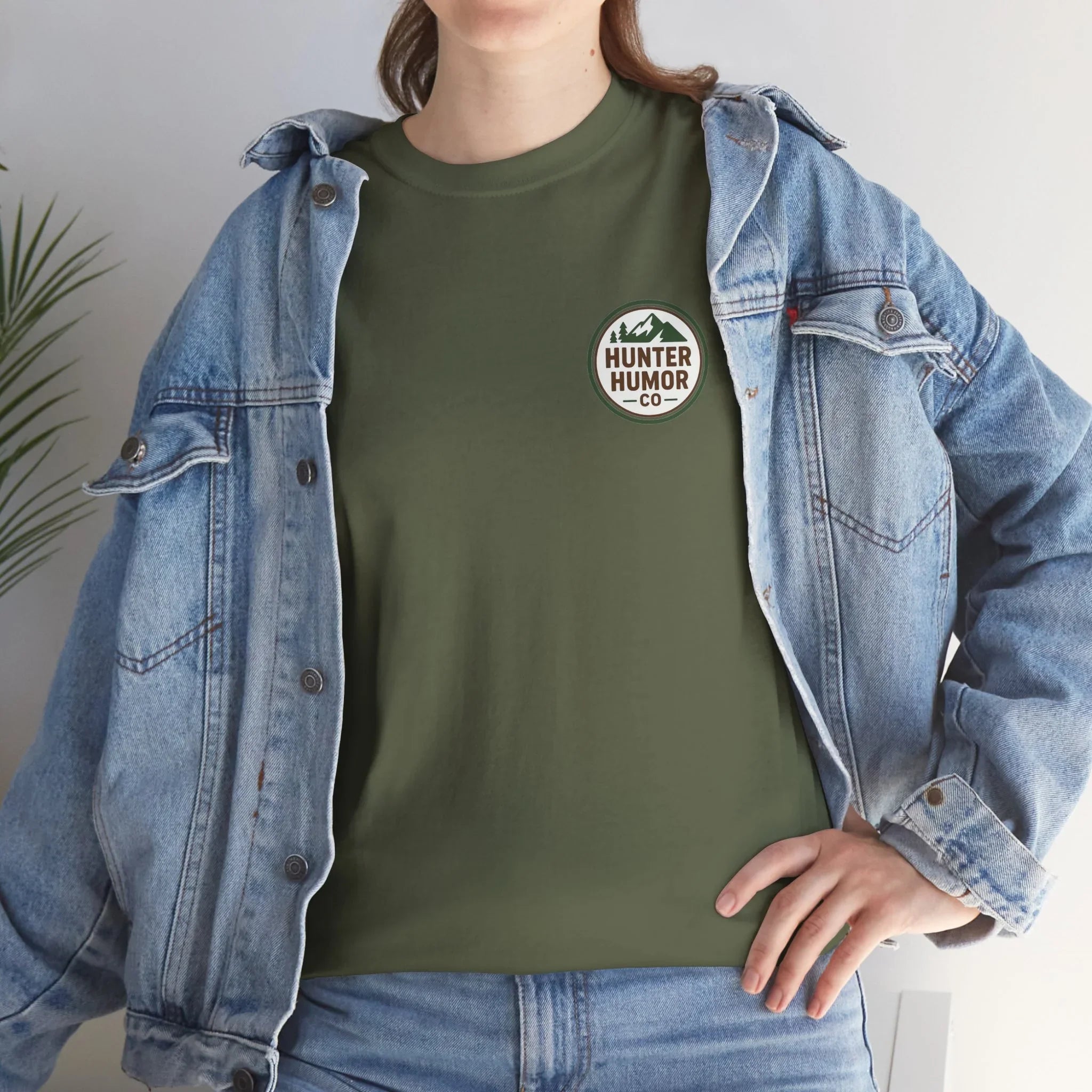 Woman in green Hunter Humor Co t-shirt and denim jacket standing indoors