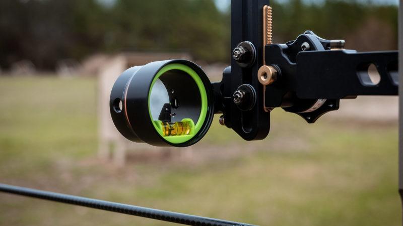Close-up of bow sight installation outdoors, archery equipment in natural setting