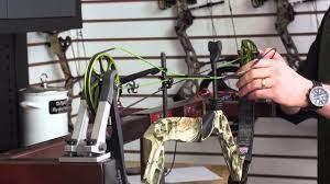 Person installing string and cable on compound bow in outdoor sports shop