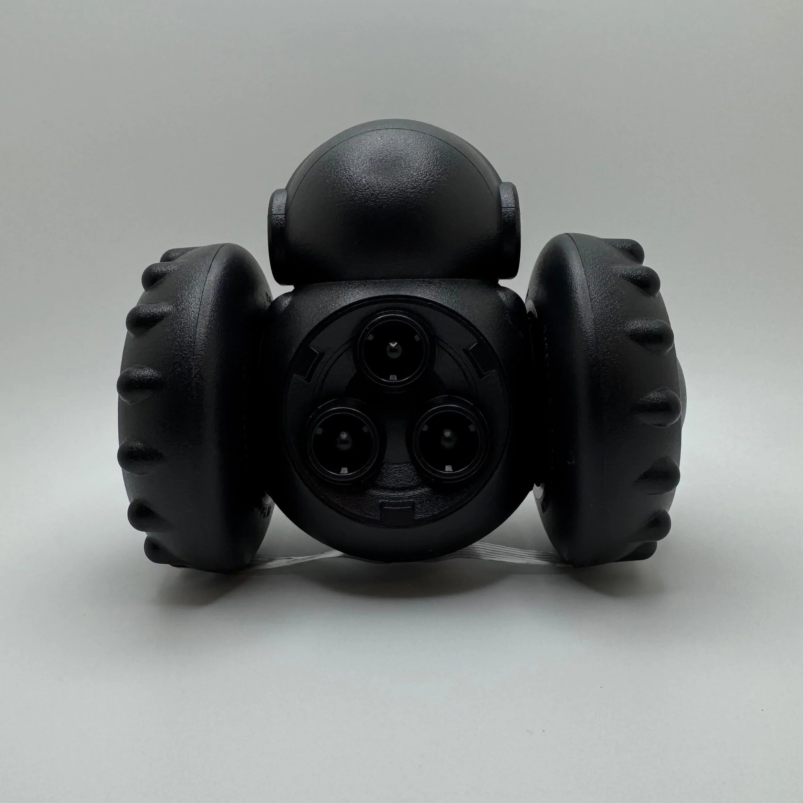 Black rolling pet toy with triple laser emitters on light gray background