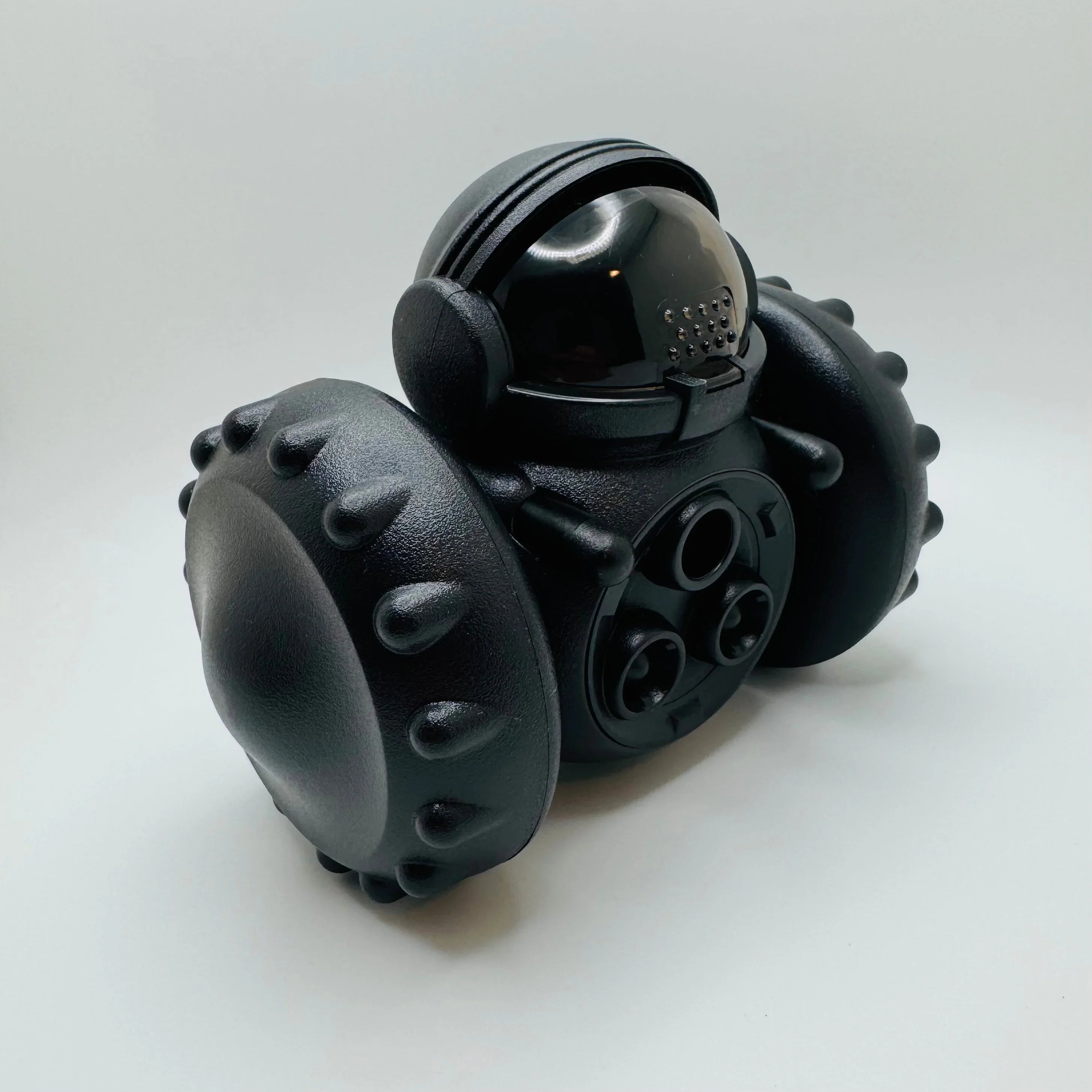 Black robot pet toy with textured wheels and a glossy helmet on white background