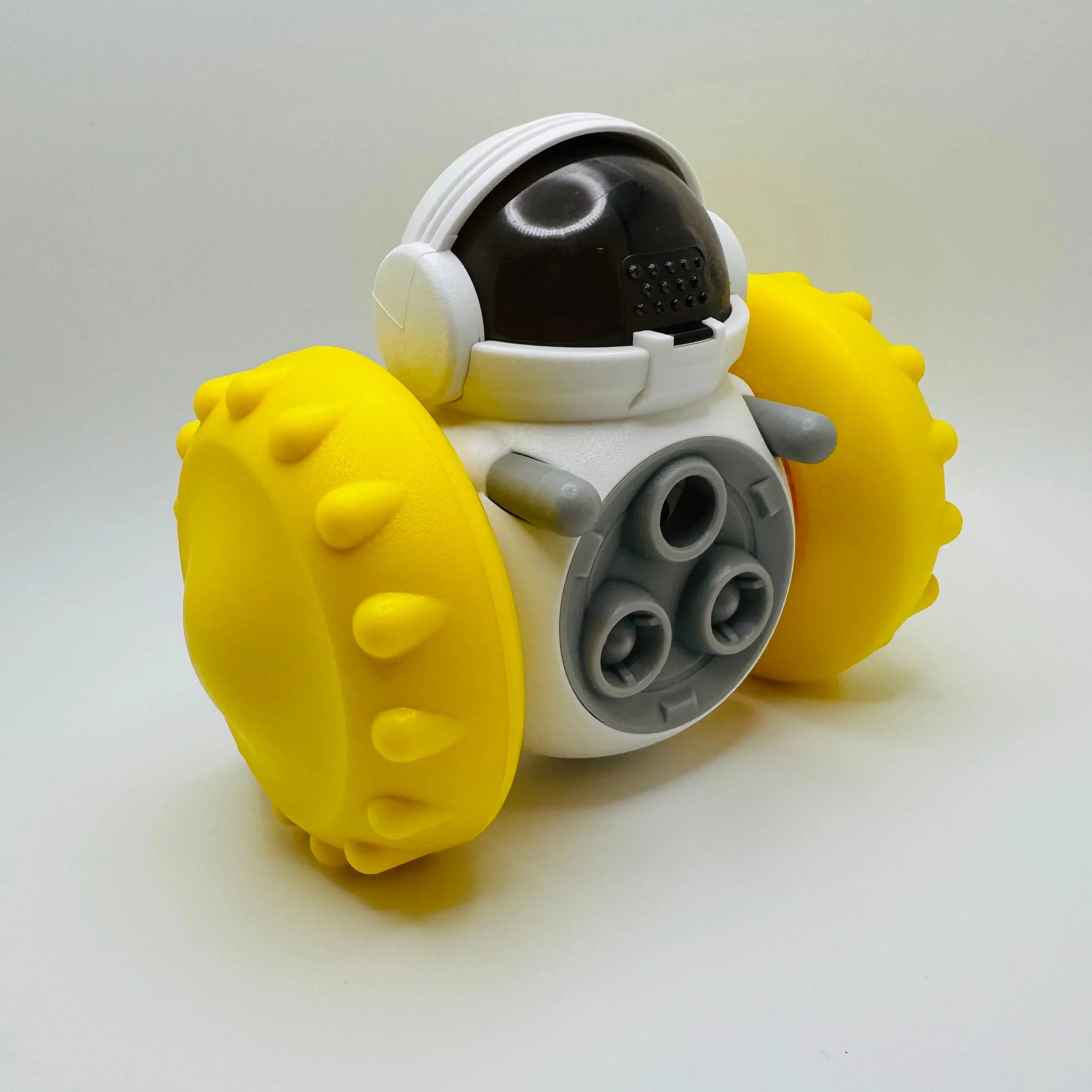 Robot dog toy with yellow spiked wheels and astronaut helmet on white background