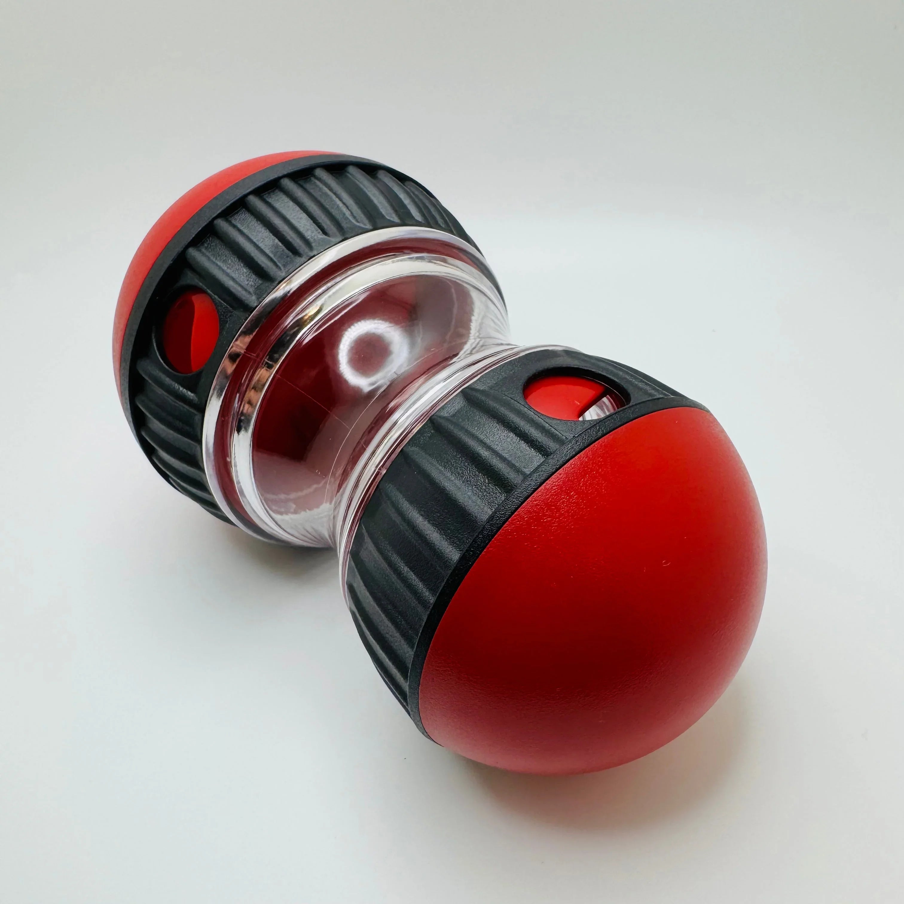 Red and black interactive dog treat toy with clear center on white background