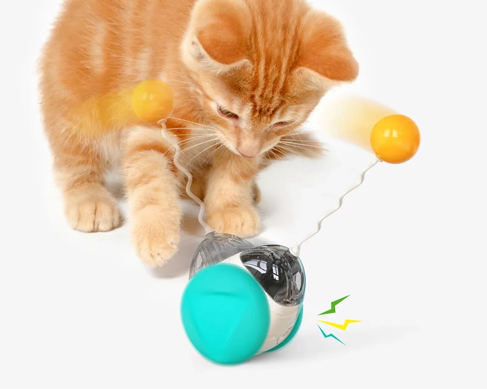 Orange kitten playing with interactive spinning cat toy with yellow balls on white background