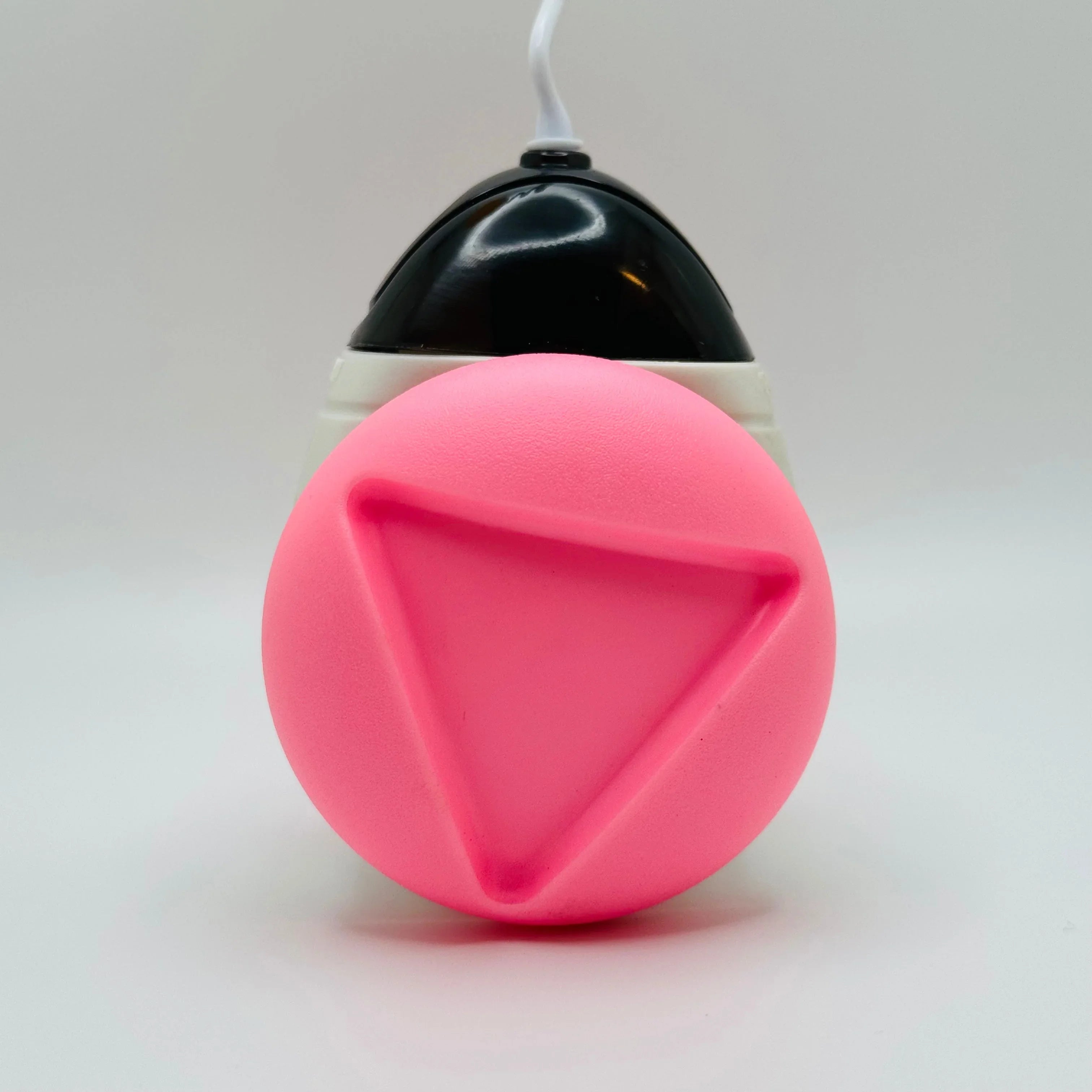Pink triangle pet toy with black and white dispenser on white background