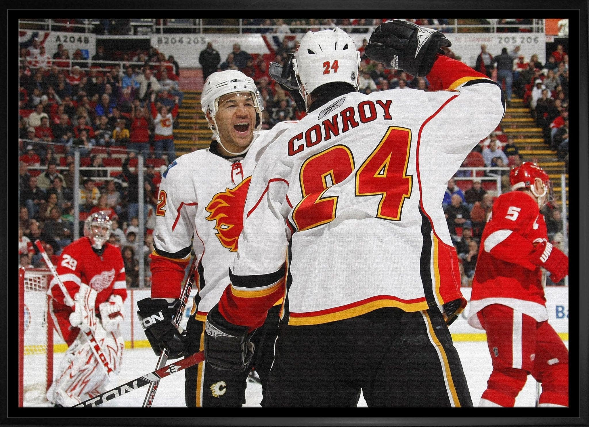 Calgary Flames hockey players celebrate on ice against Detroit Red Wings, arena background