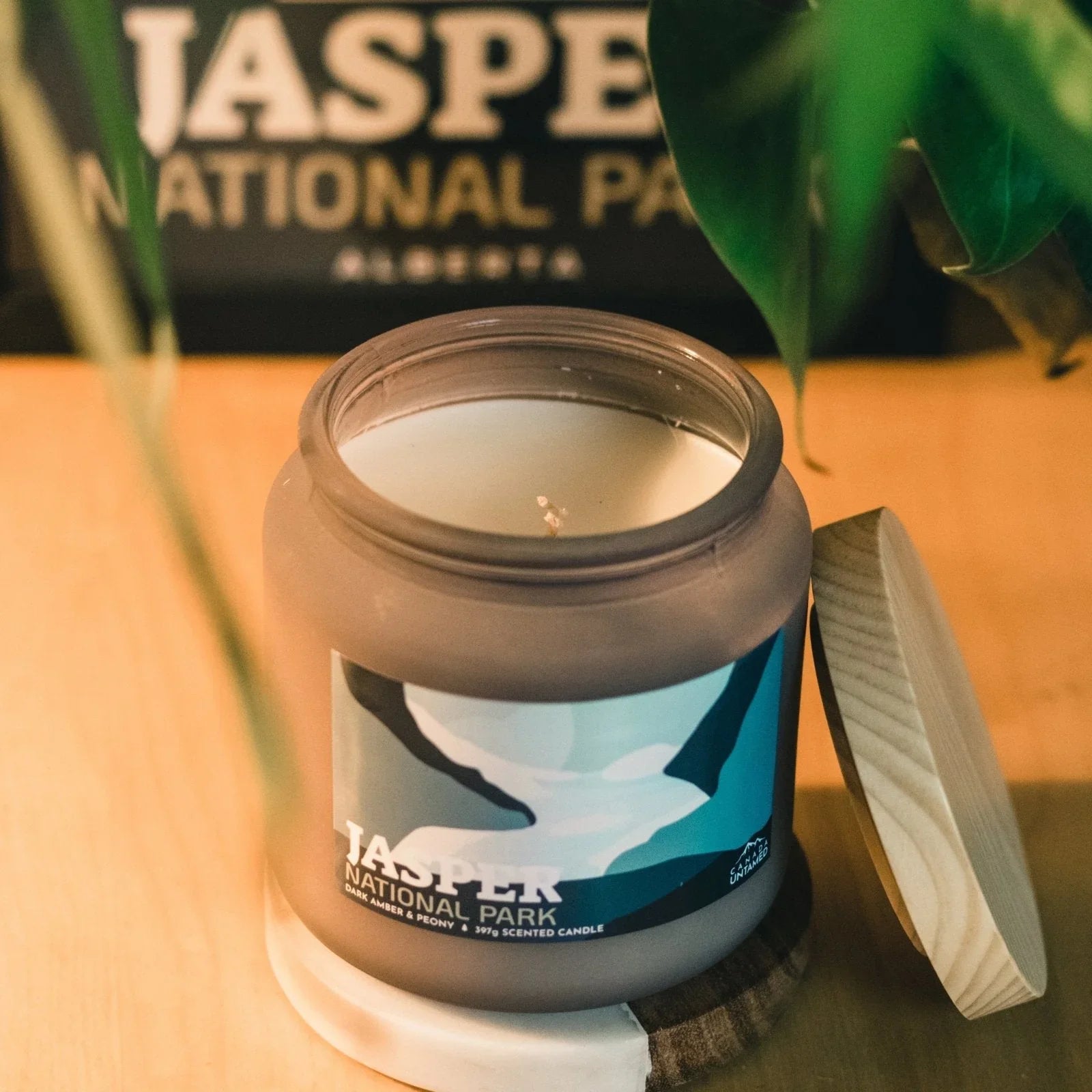 Jasper National Park dark amber peony scented candle jar on wooden table