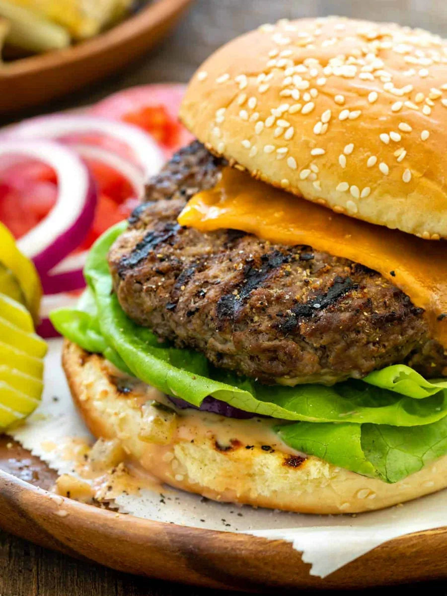 Juicy grilled cheeseburger on sesame bun with lettuce, cheddar cheese, pickles, onions, tomato
