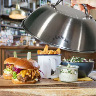 Cheeseburgers, fries, salad, and sauces served on a wooden board in a casual restaurant setting