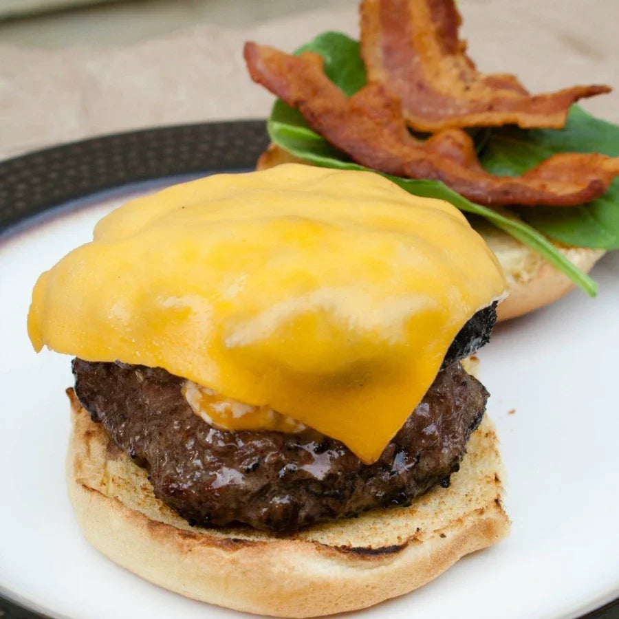 Cheeseburger with melted cheddar, beef patty, bacon and spinach on a bun