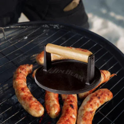 Jim Beam grill press on sausages cooking outdoors on a barbecue grill
