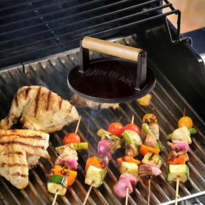 Grill with chicken breasts, colorful veggie skewers, and a Jim Beam grill press.