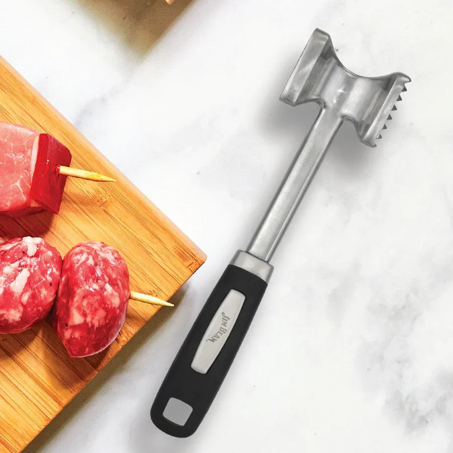 Stainless steel meat tenderizer with black handle next to raw skewered meat on a bamboo board