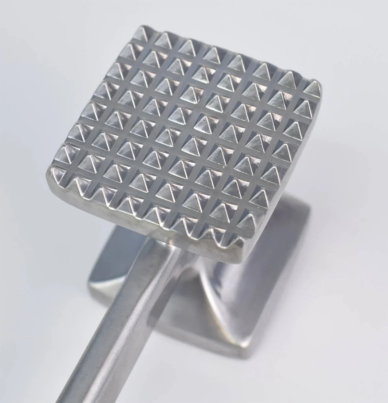 Close-up of a stainless steel meat tenderizer with a textured square head