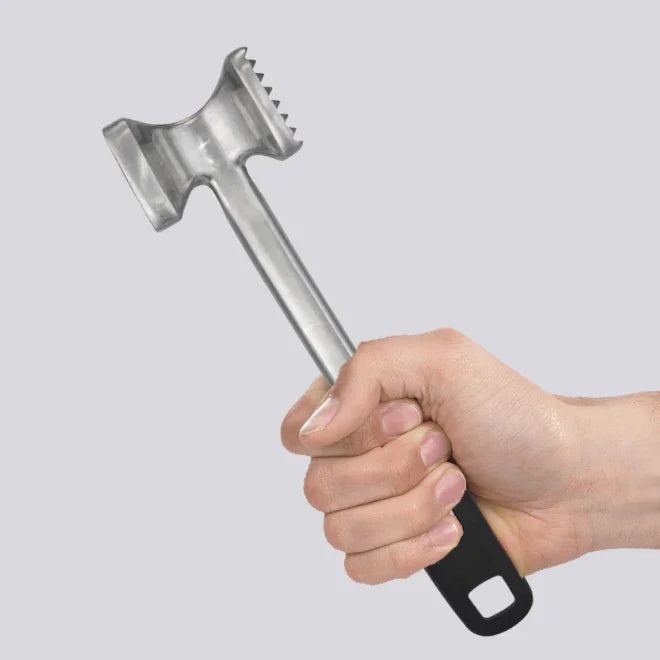 Hand holding stainless steel meat tenderizer with black handle and spiked mallet head