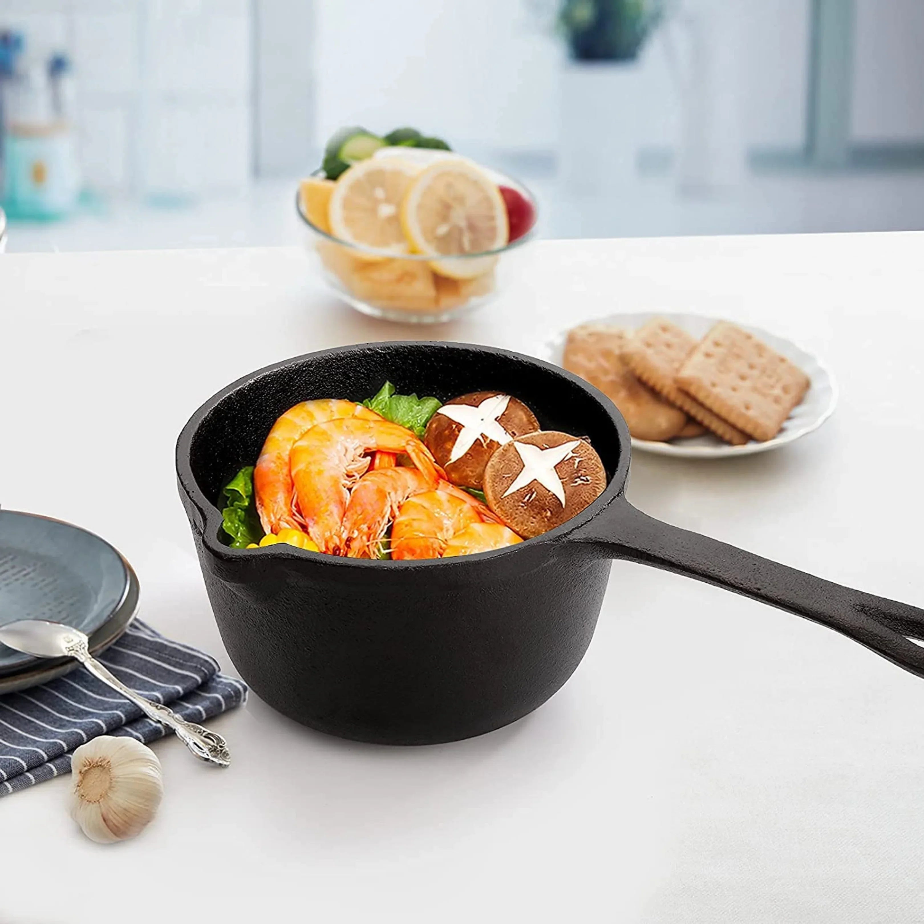 Cast iron saucepan with shrimp, mushrooms, and greens on a kitchen table