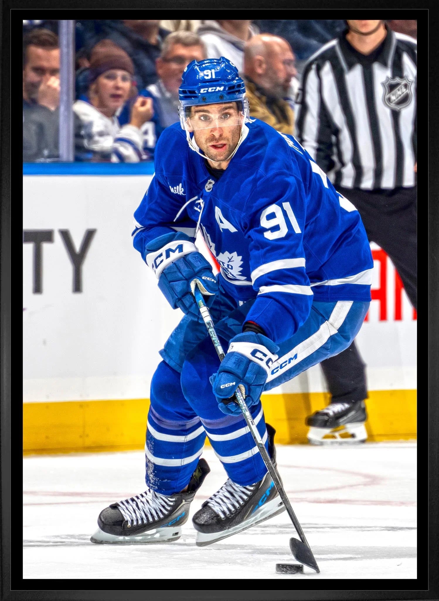 Toronto Maple Leafs hockey player in blue jersey skating with stick on ice during game