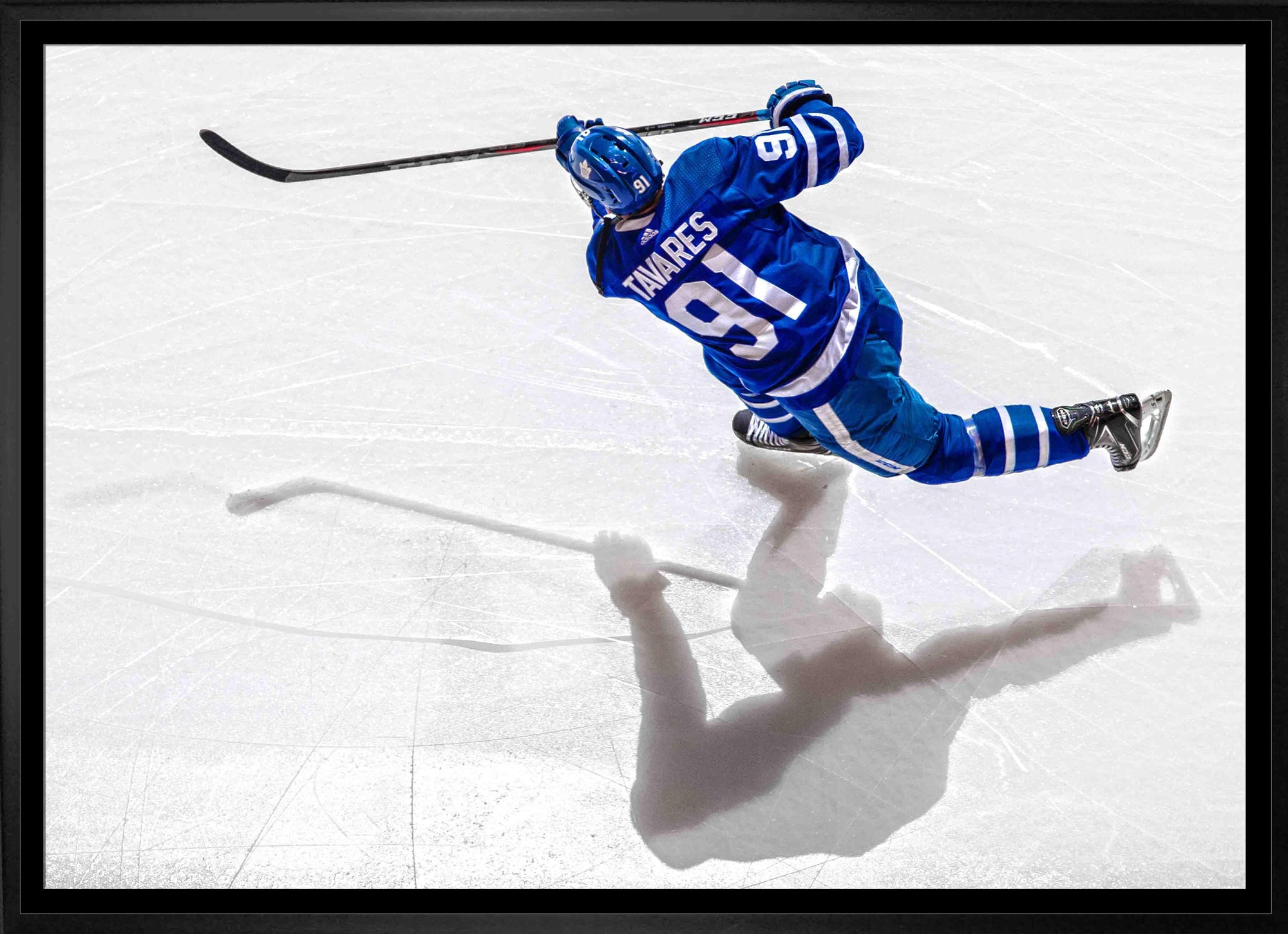 Hockey player in blue jersey number 91 shooting puck on ice rink