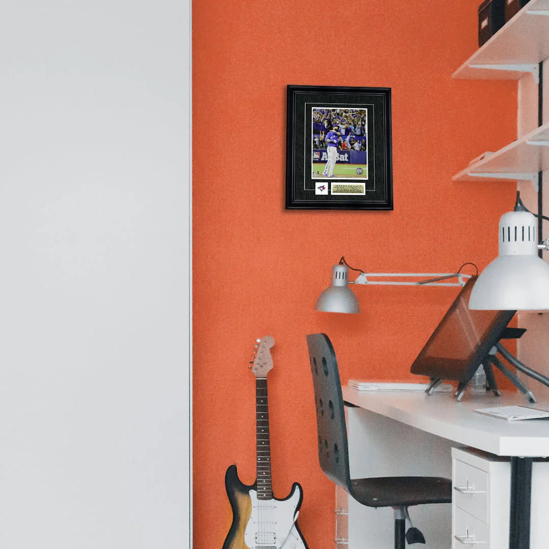 Modern home office with orange wall, electric guitar, framed sports photo, and desk lamp.