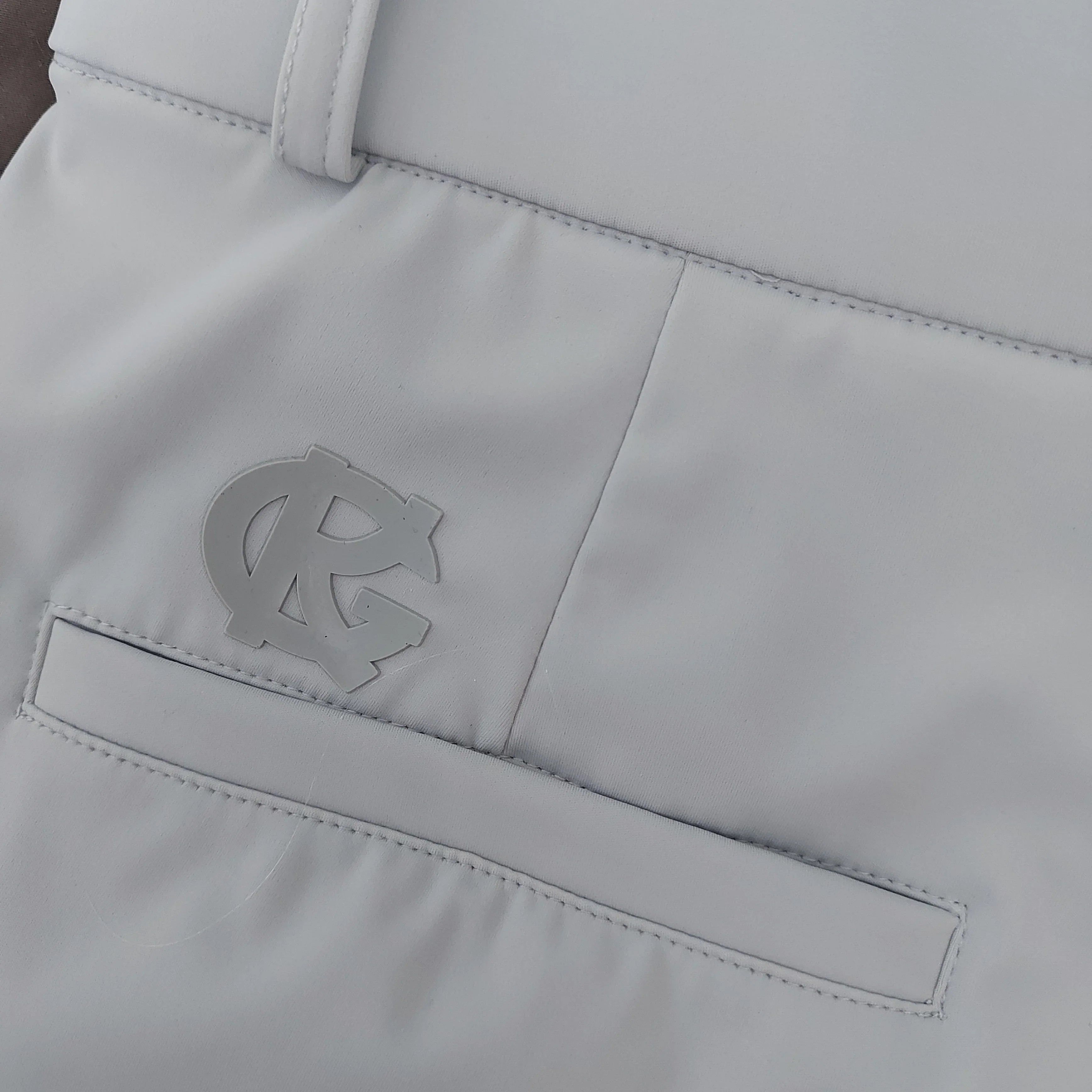 Close-up of white pants back pocket with RG embossed logo and belt loop detail