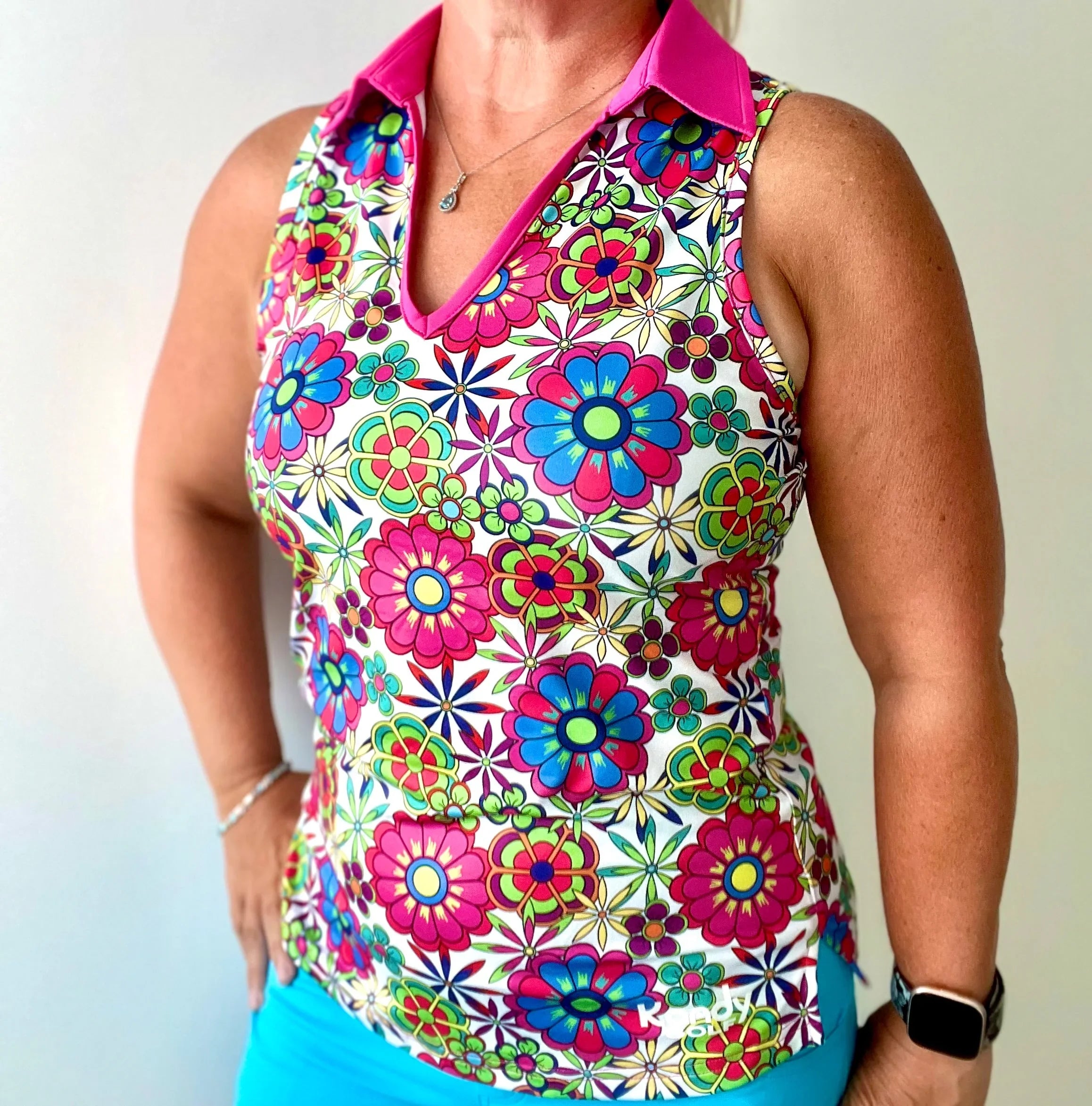 Woman wearing sleeveless floral print golf polo top with pink collar and bright colors