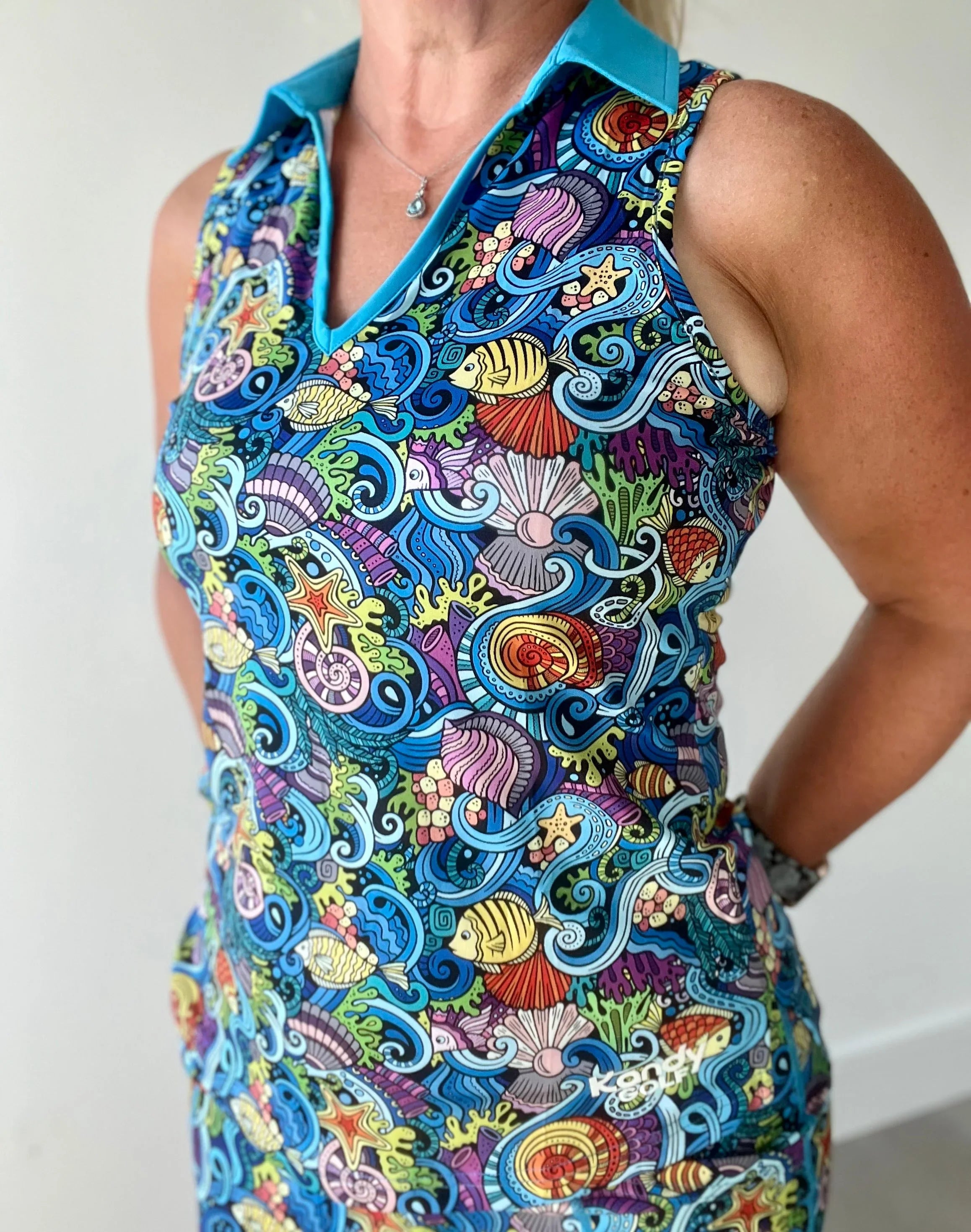Woman wearing sleeveless dress with colorful ocean-themed seashell and fish print