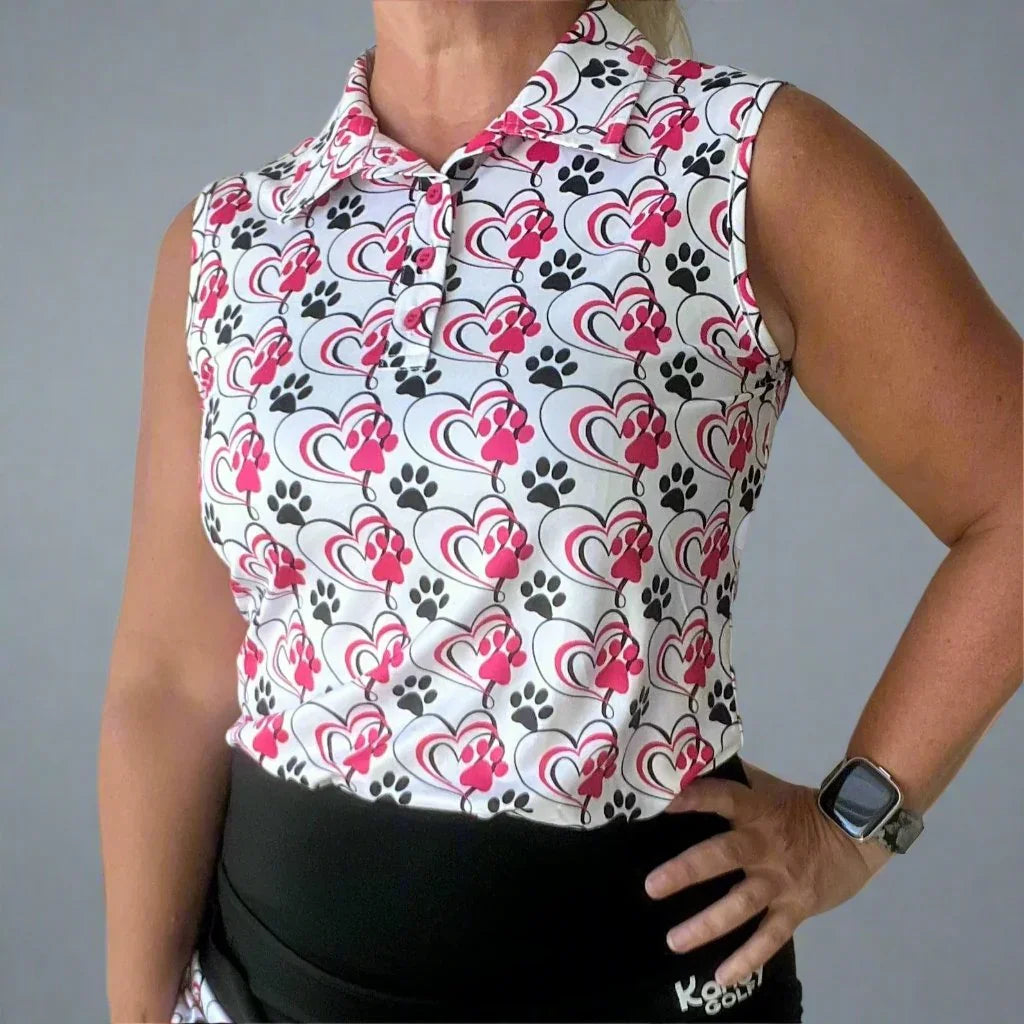 Woman wearing sleeveless golf shirt with pink hearts and black paw prints pattern